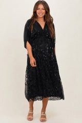 woman wearing a black maternity dress with a flowy silhouette and sequin detailing, showing her baby bump