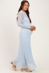 woman wearing a light blue long sleeve maternity dress with a flowing skirt and holding her baby bump