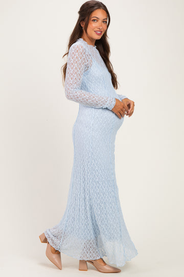 woman wearing a light blue long sleeve maternity dress with a flowing skirt and holding her baby bump