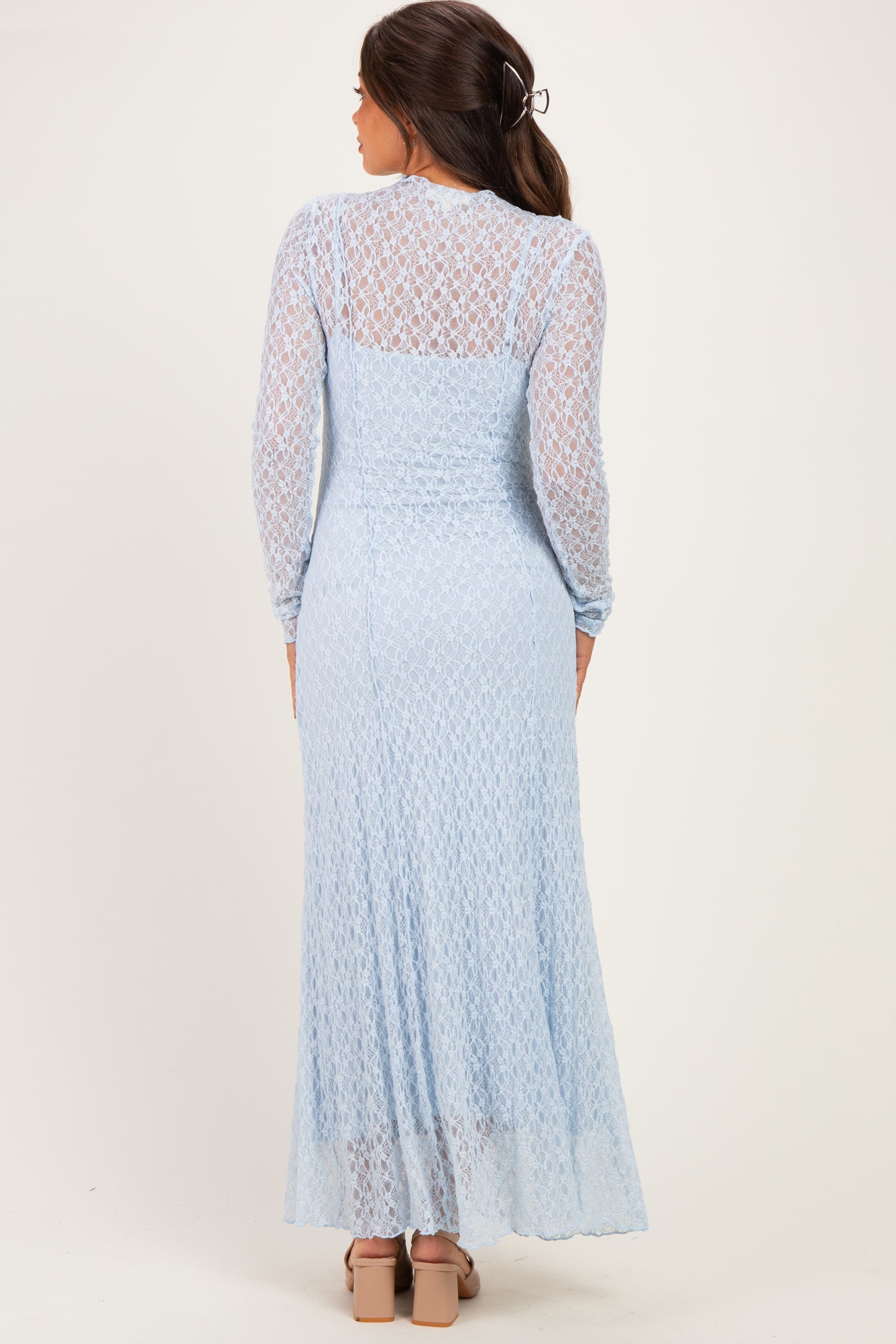 woman wearing a light blue lace maternity dress with long sleeves, showing the back view and a flowing skirt