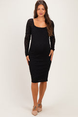 woman wearing a black lace long sleeve maternity dress, showing her baby bump