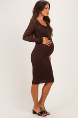 woman wearing a brown maternity dress that hugs her baby bump, styled with a scoop neckline and long sleeves