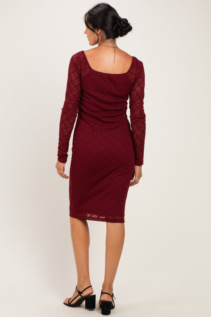 woman wearing a burgundy long sleeve fitted dress with a lace detail and a scooped back