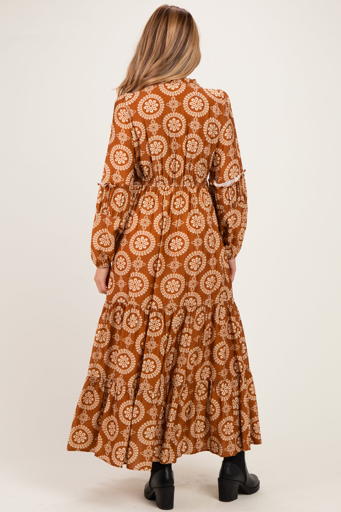 woman wearing a brown floral print maternity maxi dress with long sleeves and tiered hem. baby bump not visible