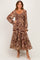 woman wearing a long brown paisley print maxi dress with puff sleeves and a tiered skirt
