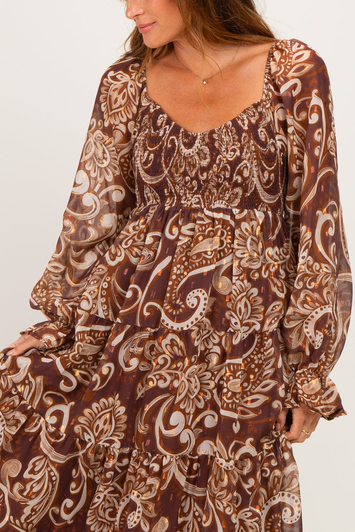 woman wearing a brown paisley print long sleeve dress with tiered ruffles and a smocked bodice