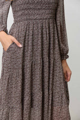 woman wearing a brown floral smocked maxi dress with long sleeves and pockets