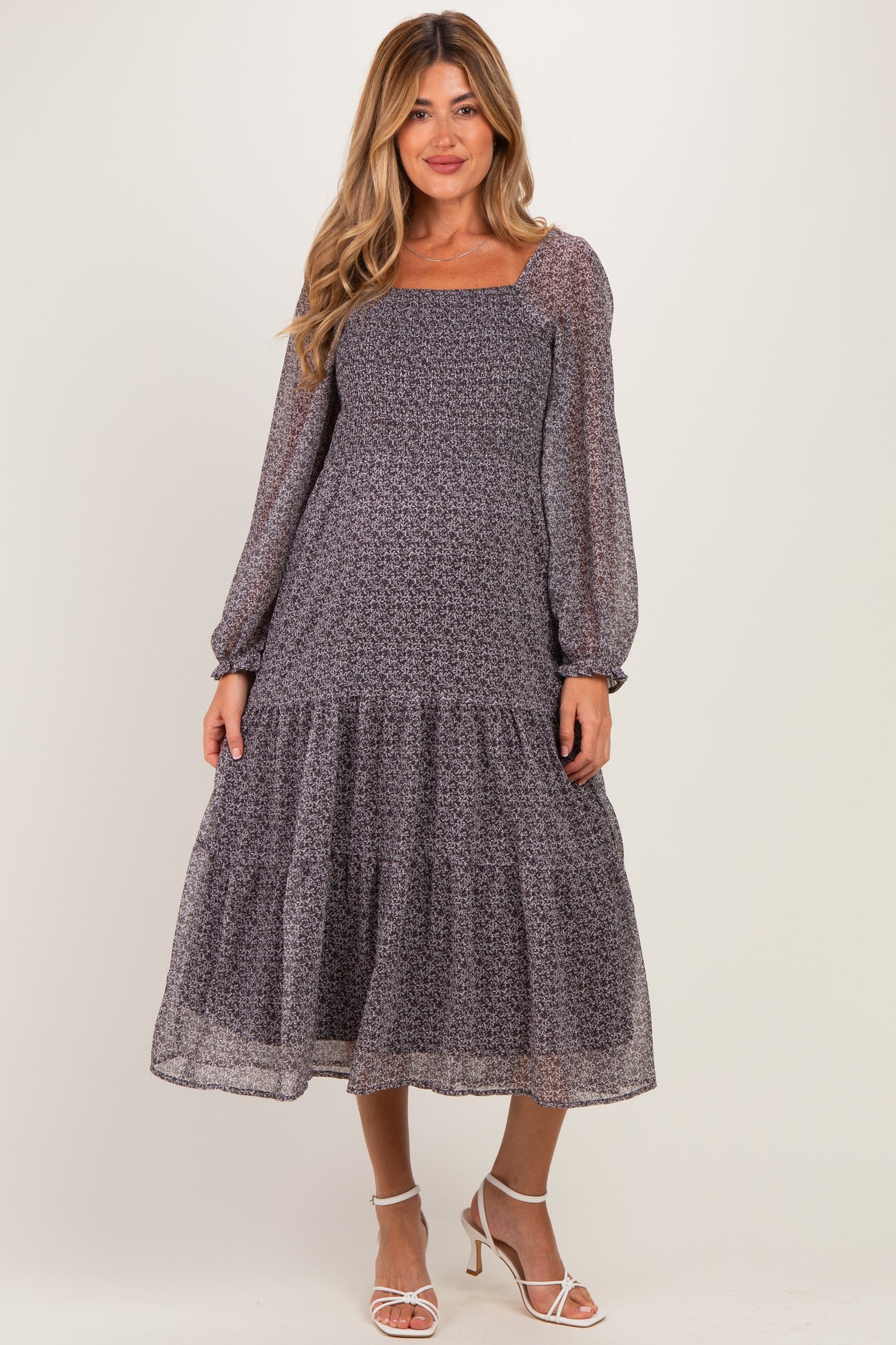 woman wearing a patterned long sleeve maternity dress with a tiered skirt and square neckline