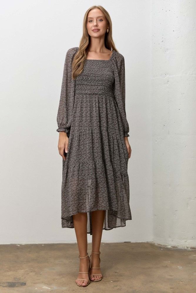 woman wearing a gray floral long sleeve midi dress with a square neckline and ruffled hem