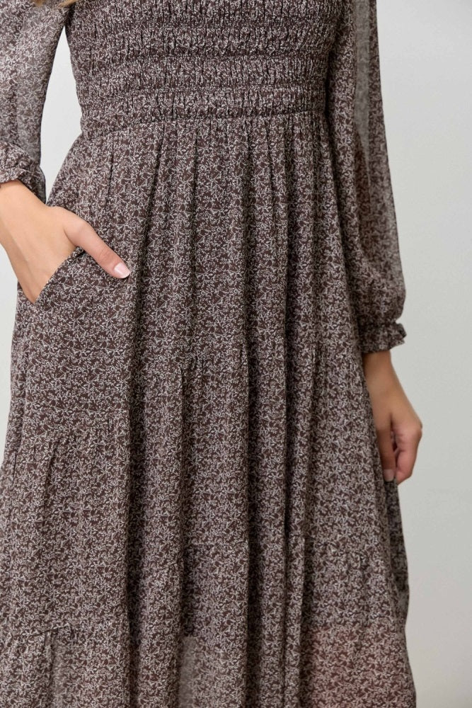 woman wearing a brown floral smocked maxi dress with long sleeves and pockets