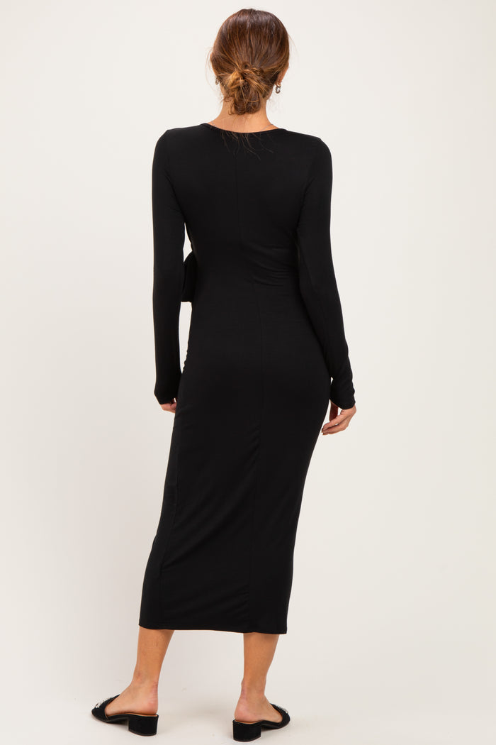 woman wearing a black long sleeve midi dress, viewed from the back, fitted silhouette, and styled with black flat sandals