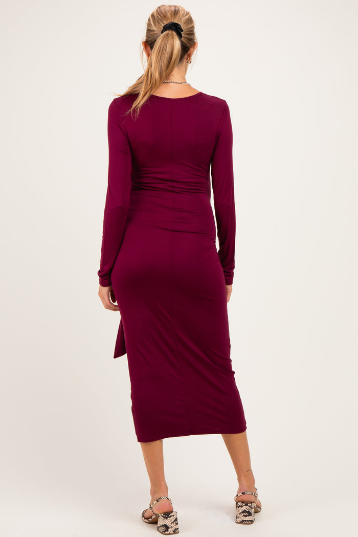 woman wearing a burgundy long sleeve maternity dress, fitted style with a side slit, showing her back