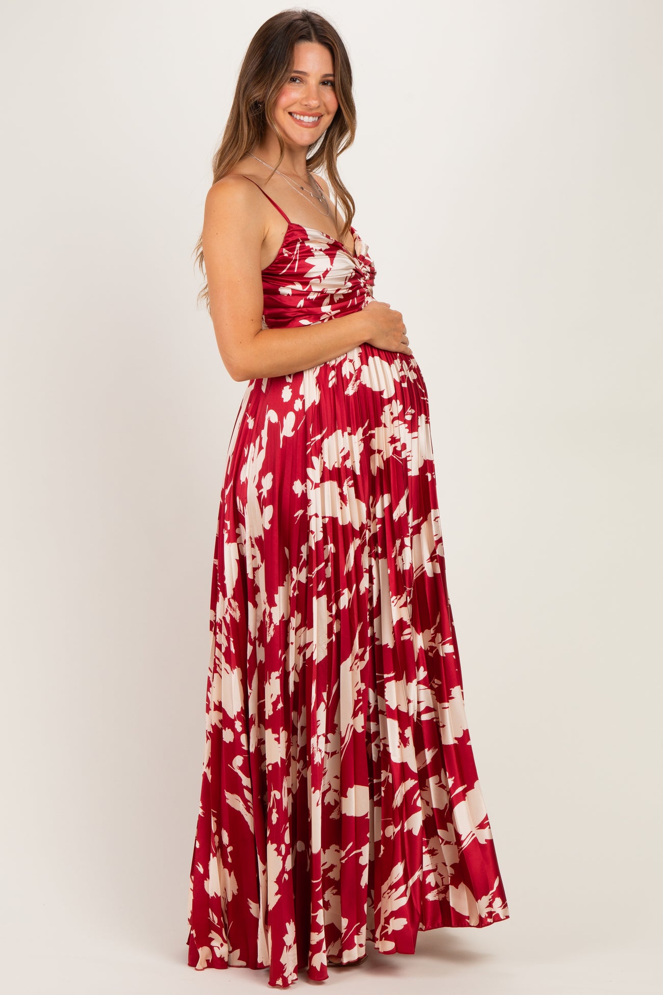 woman wearing a red and white floral maternity maxi dress and holding her baby bump