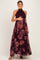 woman wearing a dark burgundy floral print maternity maxi dress and holding her baby bump