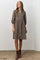 woman wearing a brown floral button-up dress with puffed sleeves and standing on a concrete floor