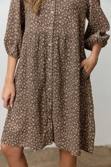 woman wearing a brown floral button-up dress with pockets and puff sleeves