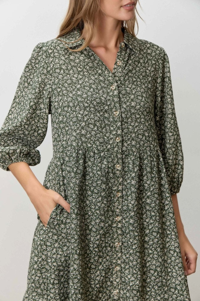 woman wearing a green floral print button-up dress with three-quarter sleeves and pockets