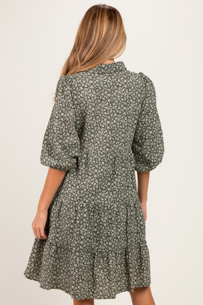 woman wearing a green floral maternity dress with puff sleeves and a tiered skirt, visible baby bump from the back