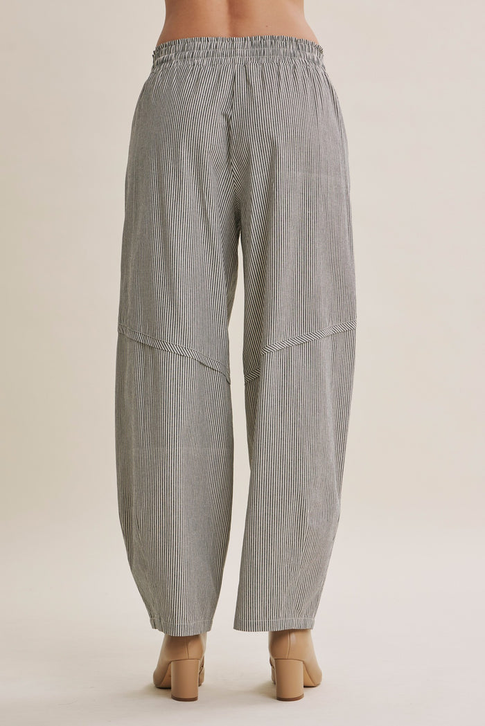 woman wearing black and white striped loose-fitting wide-leg pants, back view