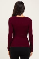 woman wearing a burgundy long sleeve fitted top, viewed from the back