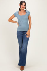 woman wearing a light blue scoop neck t-shirt and flared jeans with brown heeled boots