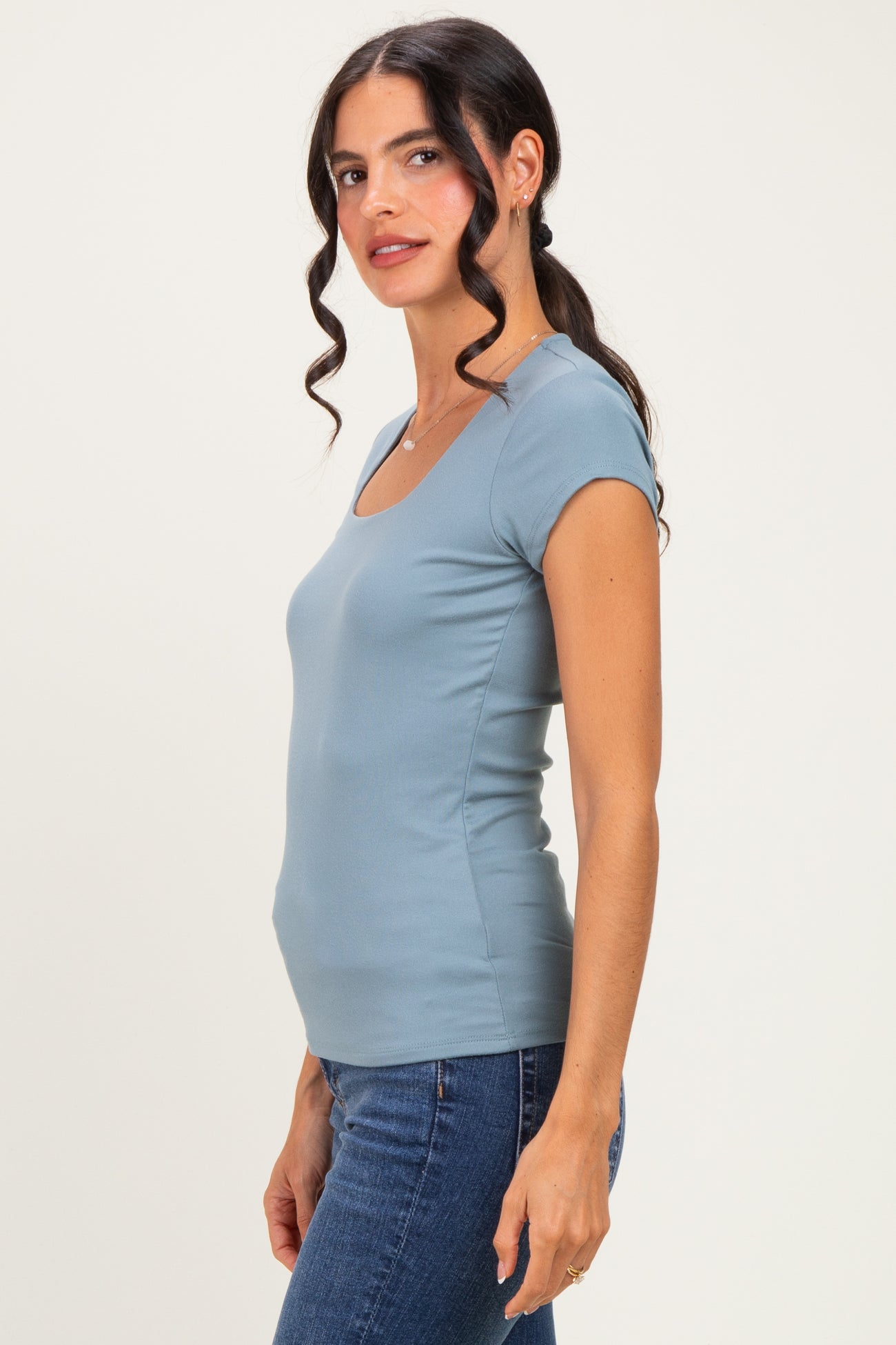 woman wearing a blue fitted short sleeve top with a square neckline, paired with denim jeans