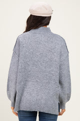 woman wearing a gray oversized turtleneck sweater with side slits and relaxed fit from the back