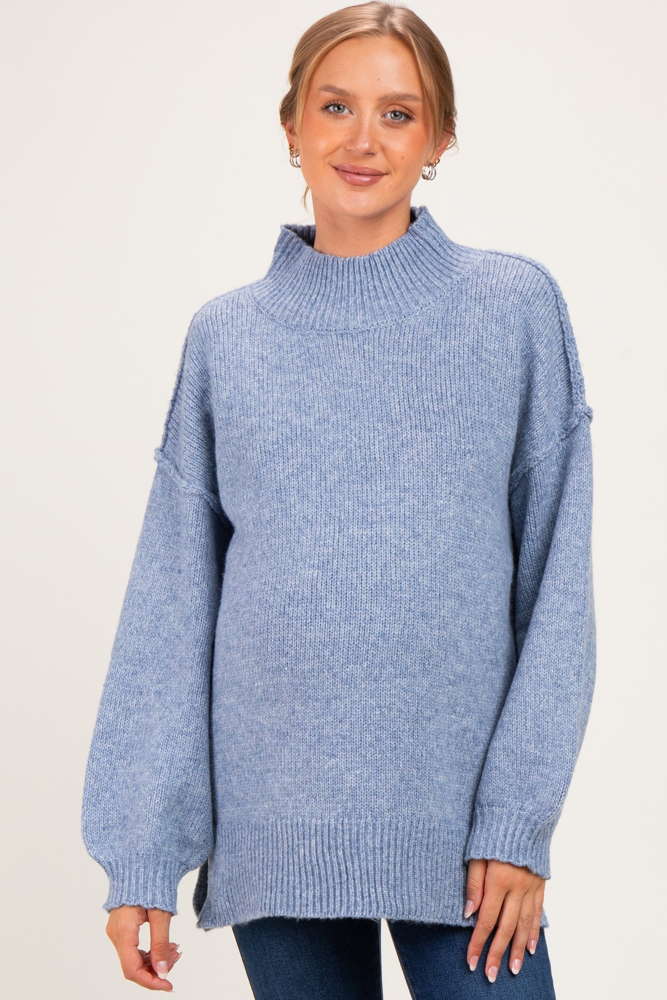 woman wearing a light blue oversized maternity sweater with a high neck and balloon sleeves