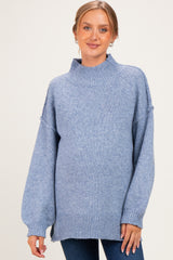 woman wearing a light blue oversized maternity sweater with a high neck and balloon sleeves