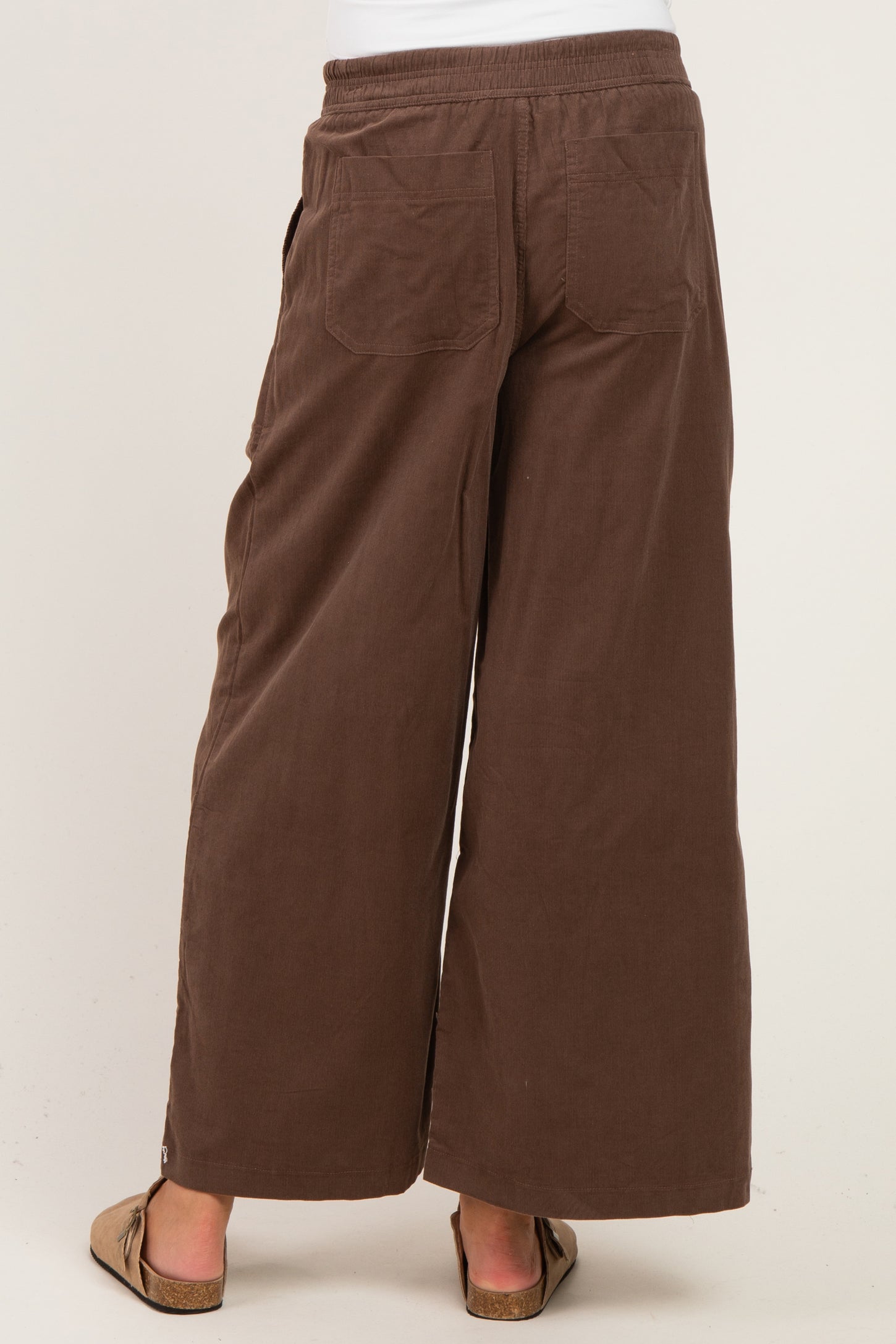 woman wearing brown wide-leg maternity pants, showing the back view and elastic waistband