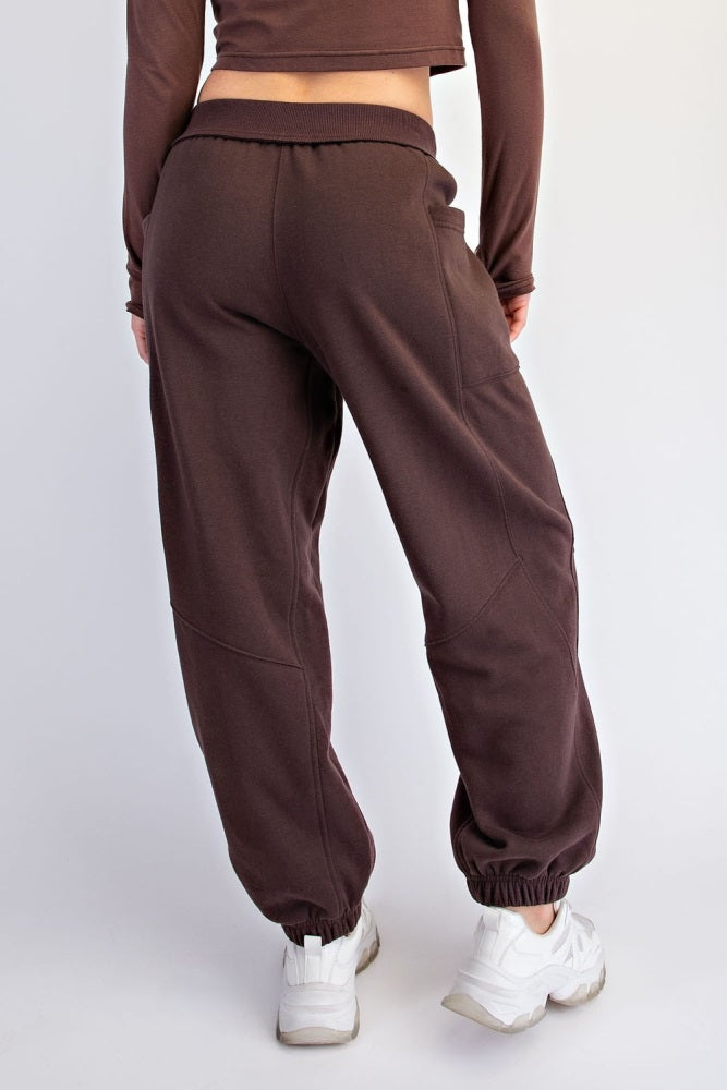 woman wearing brown sweatpants with elastic cuffs and a relaxed fit, showing the back view