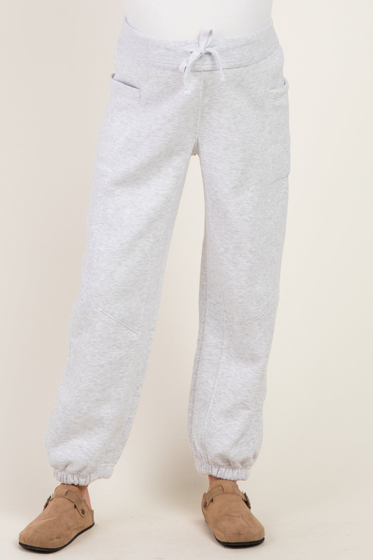 maternity wear light gray sweatpants with side pockets and elastic cuffs, model wearing them with no visible baby bump