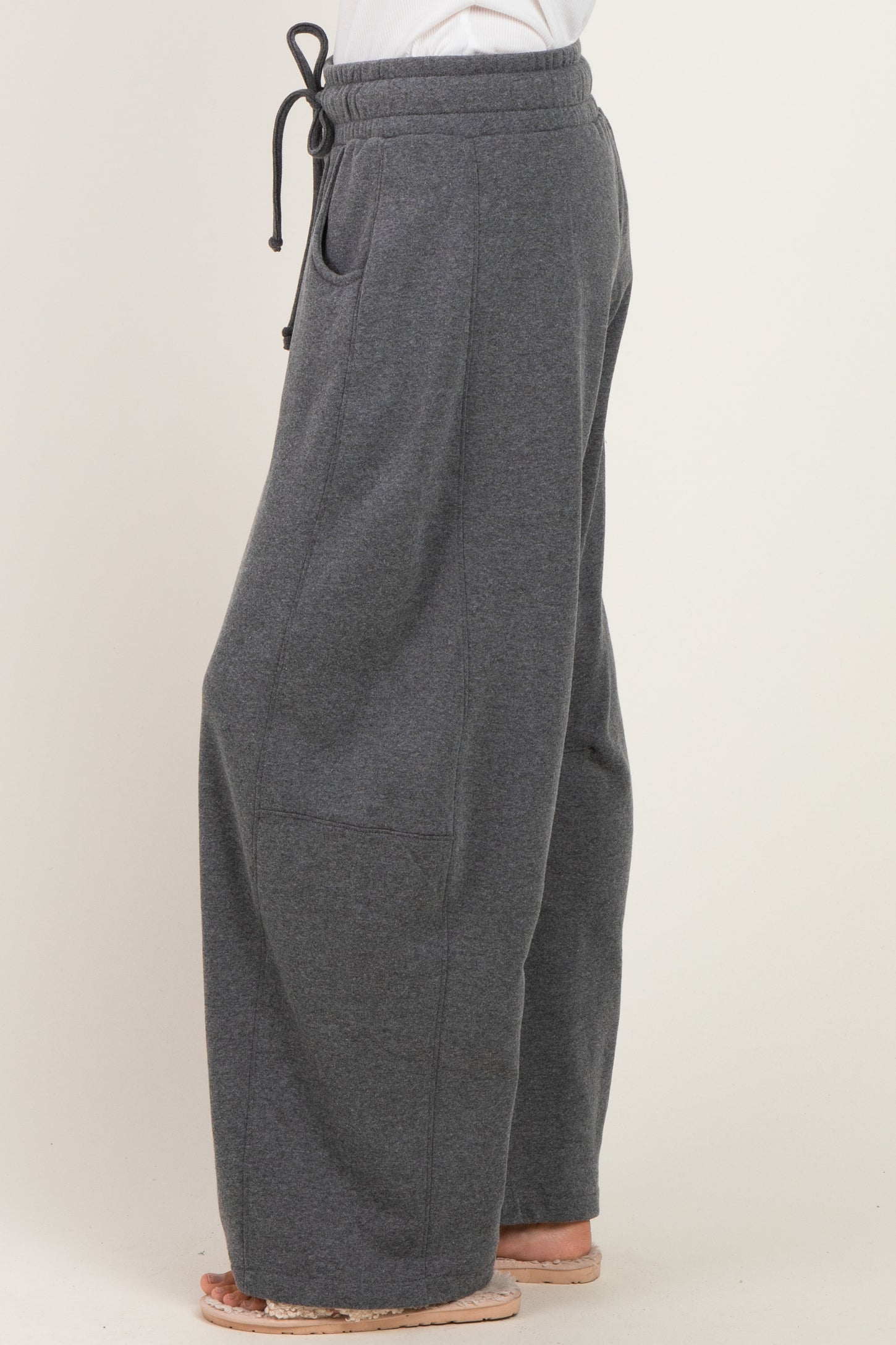 woman wearing dark gray wide-leg sweatpants with a drawstring waist and side pockets