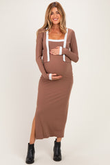 woman wearing a brown maternity dress with white trim, showcasing her baby bump and paired with black ankle boots