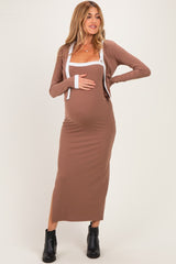 woman wearing a brown ribbed maternity dress with a white trim and a long cardigan, showing her baby bump