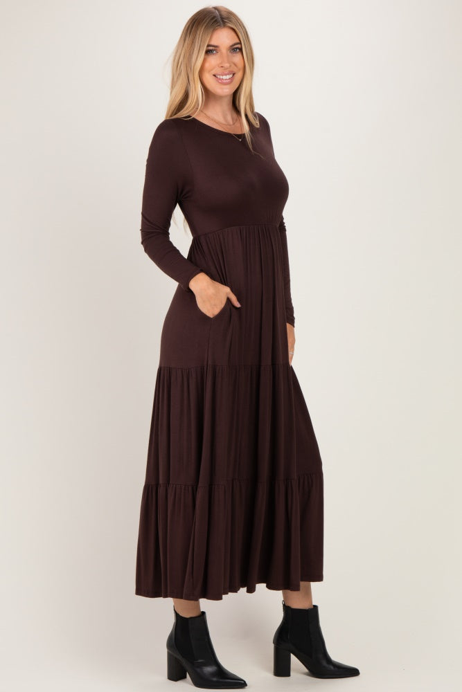 woman wearing a brown long sleeve tiered maxi dress with side pockets and black ankle boots