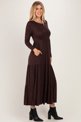 woman wearing a brown long sleeve tiered maxi dress with side pockets and black ankle boots