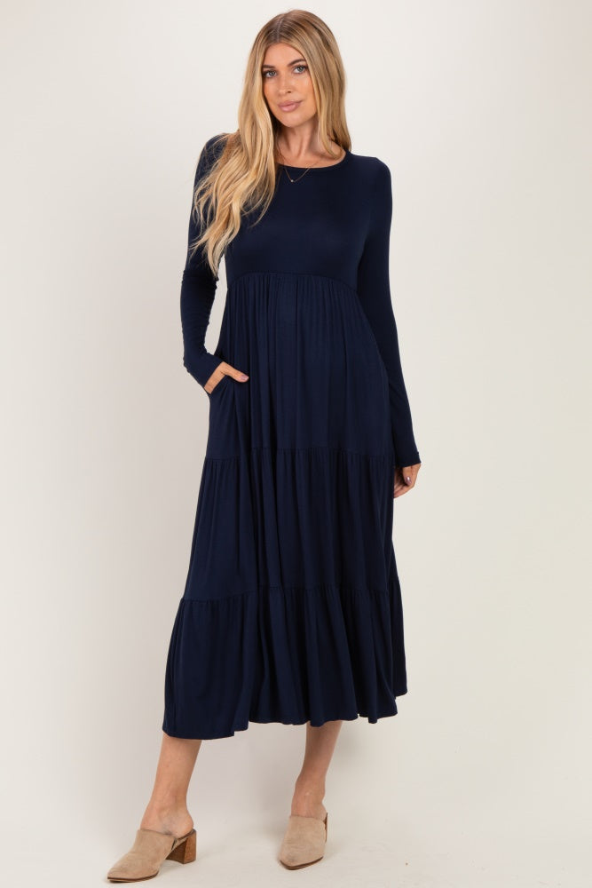 woman wearing a navy long sleeve tiered maxi dress with pockets and beige mules