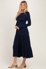 woman wearing a navy long sleeve tiered maxi dress with a fitted bodice and flared skirt