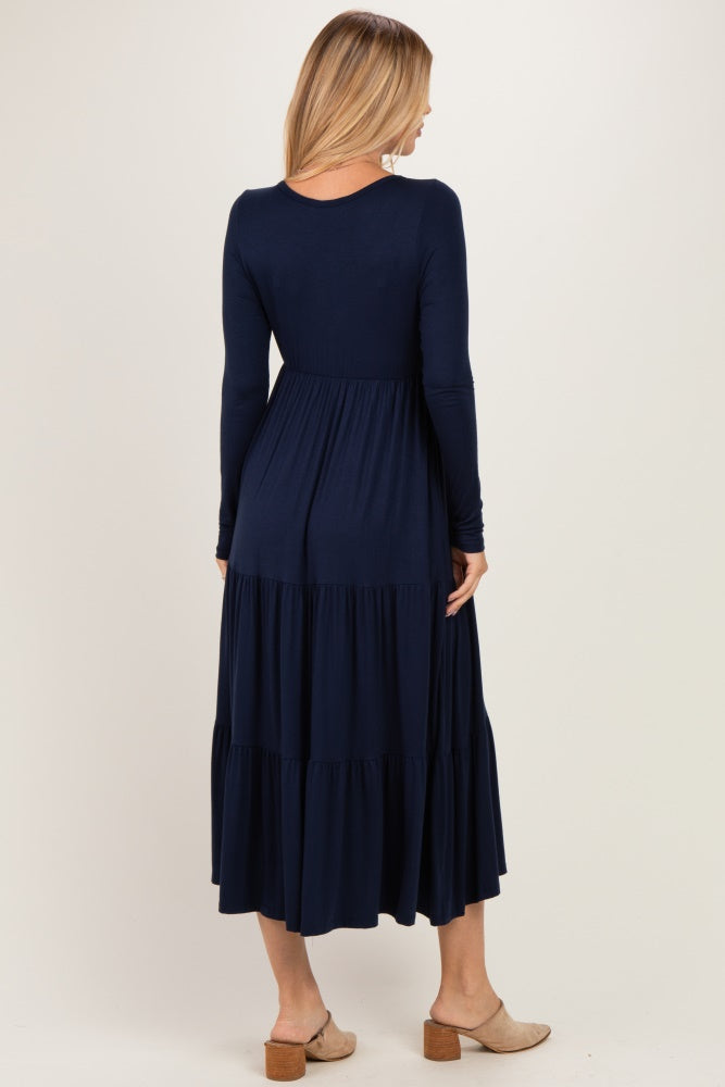 woman wearing a navy long sleeve maxi dress with tiered ruffle details and a fitted bodice, viewed from the back