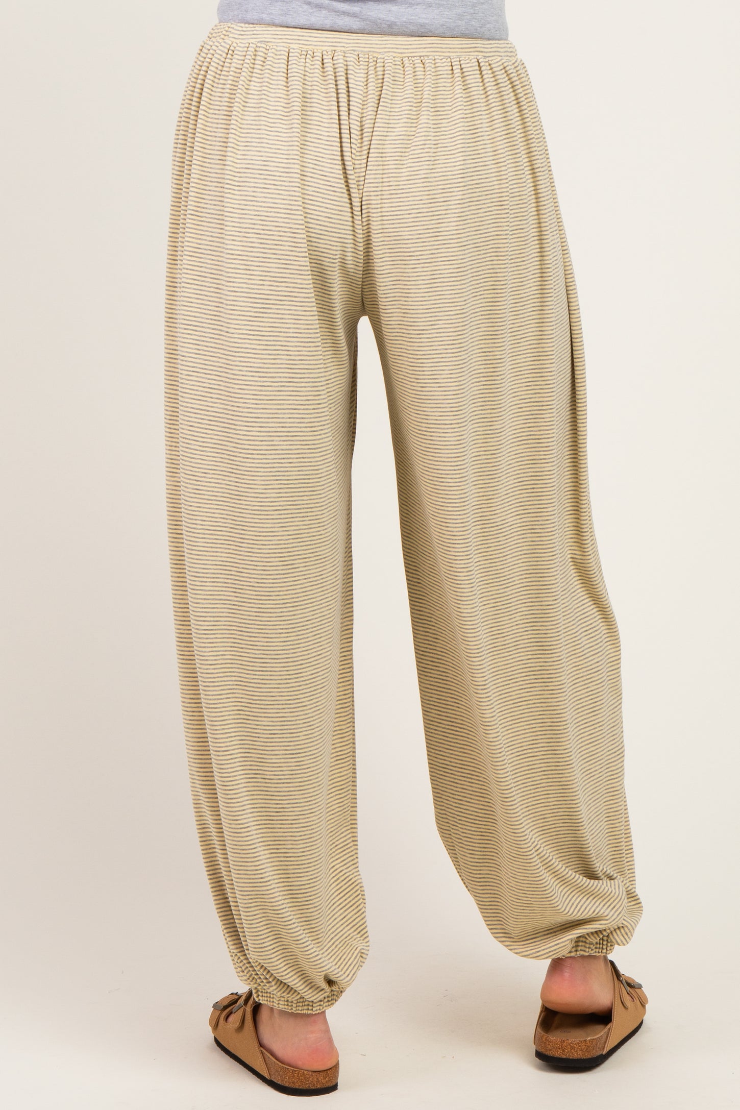 woman wearing beige striped maternity harem pants with an elastic waistband and tapered cuffs