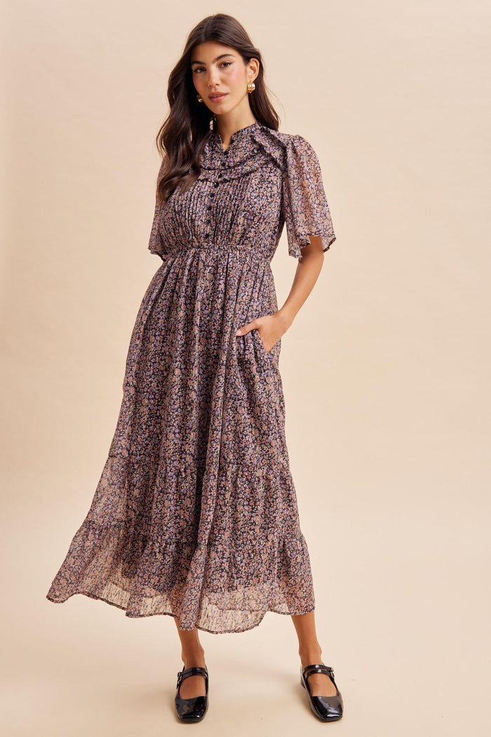 woman wearing a floral patterned maxi dress with short sleeves and pockets, styled with black flats