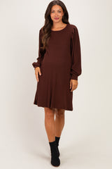 woman wearing a brown long sleeve maternity dress with puffed sleeves and a flowy skirt, highlighting her baby bump