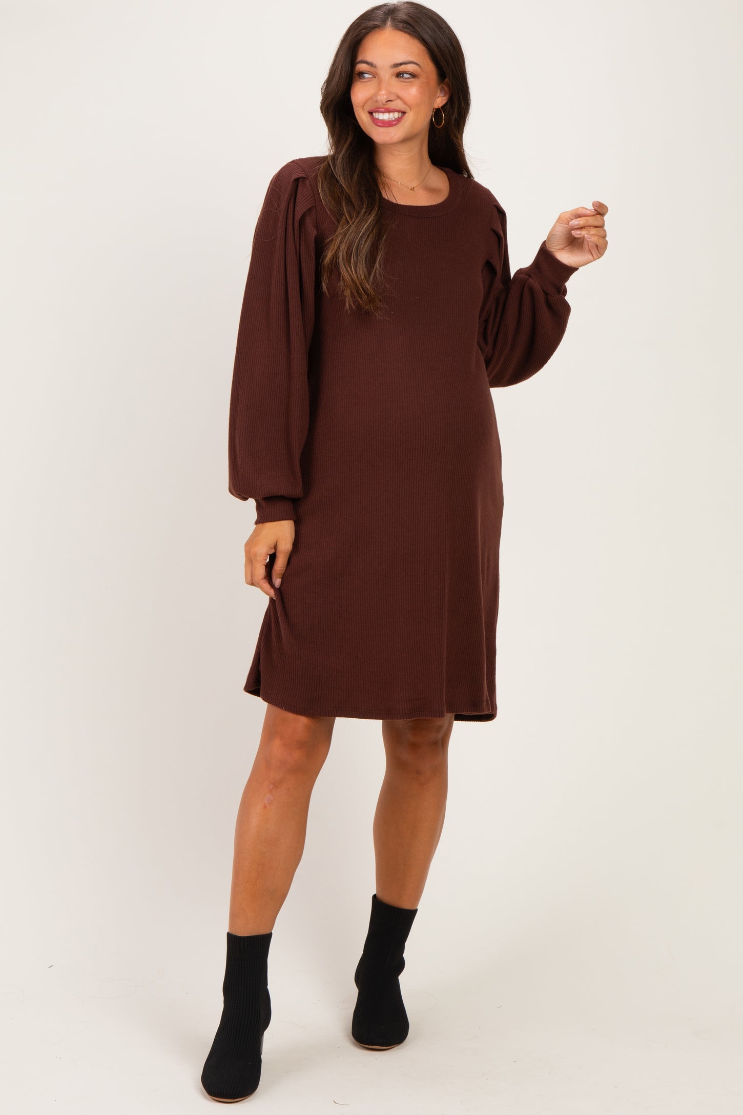 woman wearing a brown maternity dress with puff sleeves and a relaxed fit, showcasing her baby bump