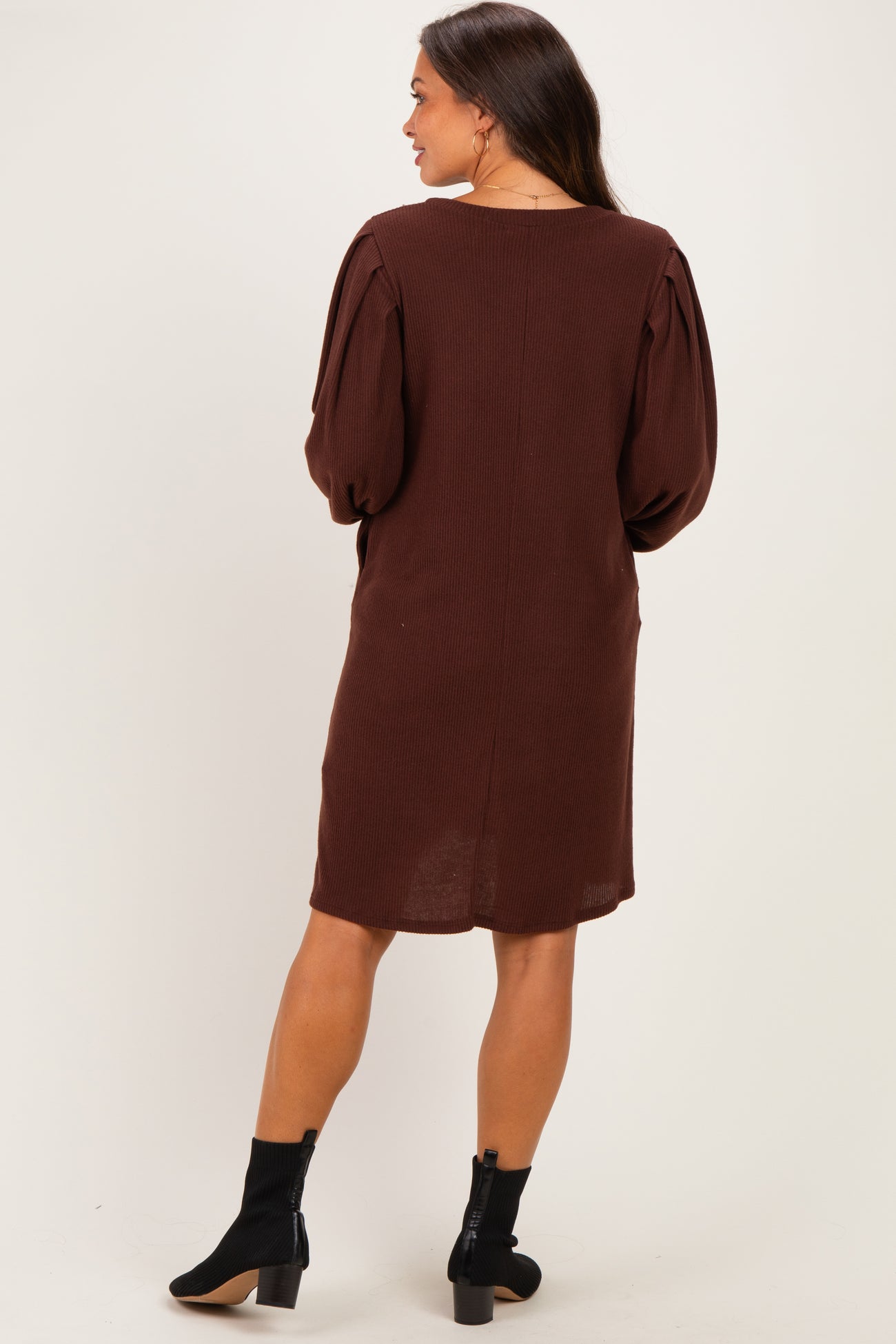woman wearing a brown maternity dress with puffed sleeves and a relaxed fit, shown from the back