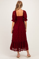 woman wearing a burgundy lace maternity dress with a smocked bodice and ruffled hem, showing her back