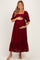 woman wearing a burgundy lace maternity dress with puff sleeves and ruffle hem, holding her baby bump