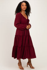 woman wearing a burgundy maxi dress with a deep v-neckline and tiered ruffle detailing, styled with heeled sandals