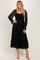 woman wearing a black lace maxi dress with smocked bodice and long sleeves, posing with an elegant stance