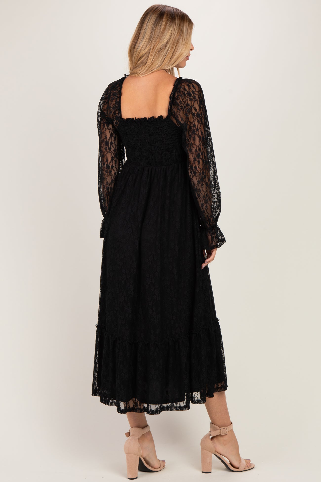 woman wearing a black lace midi dress with long sleeves and a smocked back detail